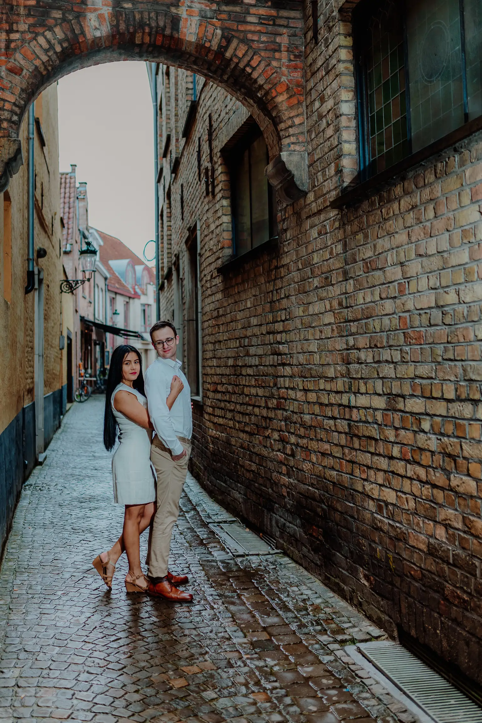 Couple in a historic brick alley under a stone arch in Bruges, Belgium – couple photoshoot