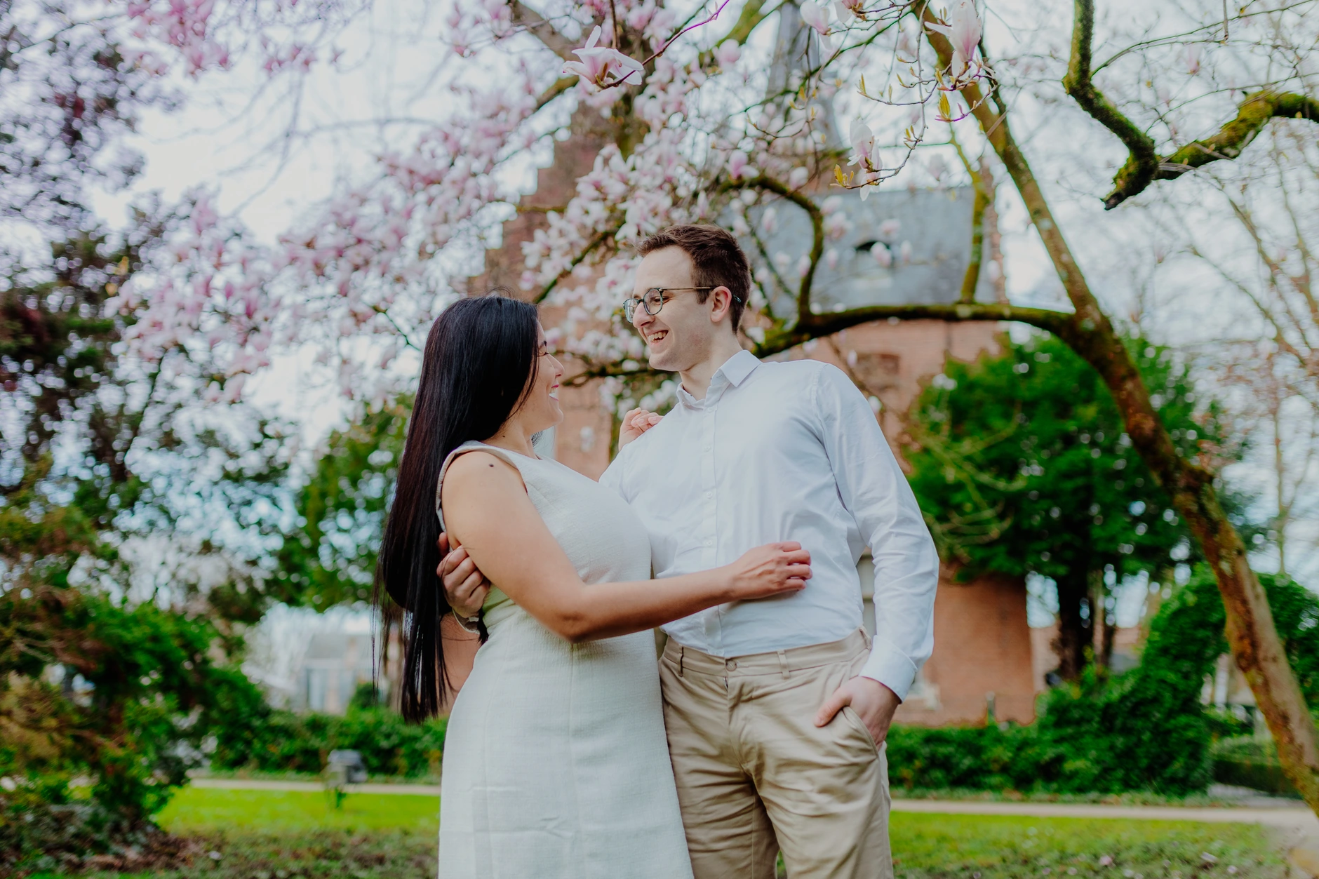 Paar in inniger Umarmung unter bluehenden Baeumen