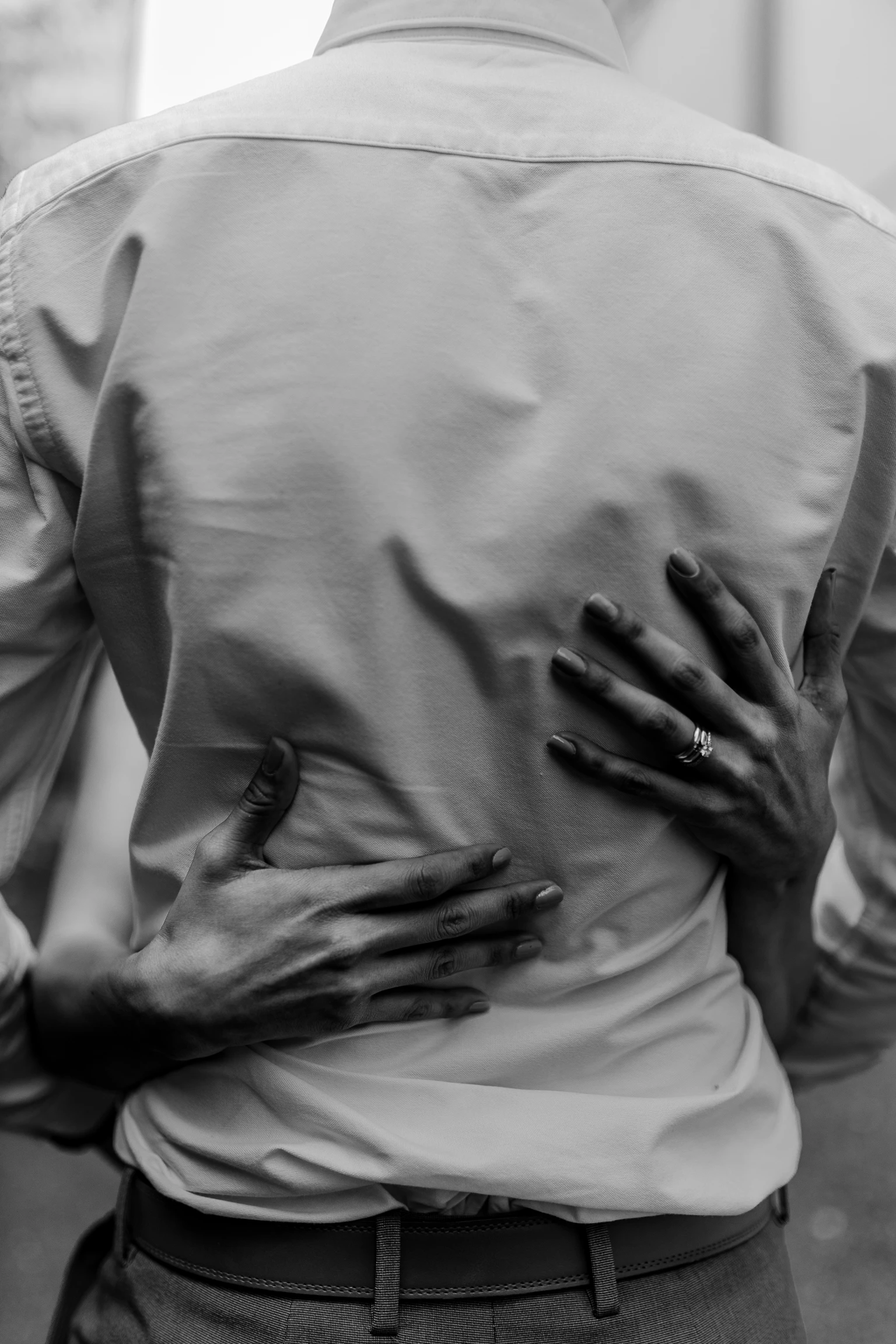 Close-up detail — groom's hand on the bride's back