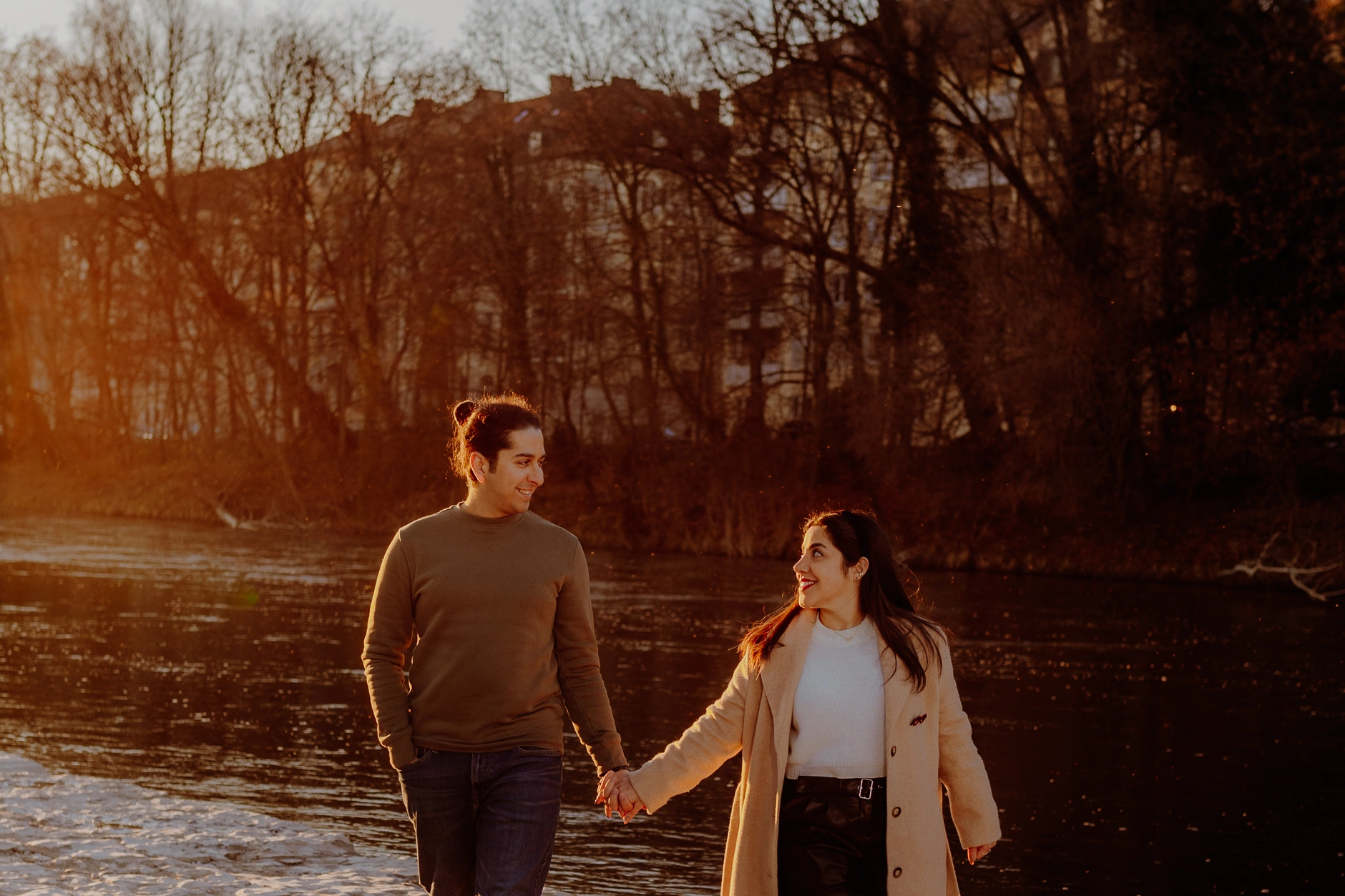 Couple walking hand in hand along the Isar at sunset