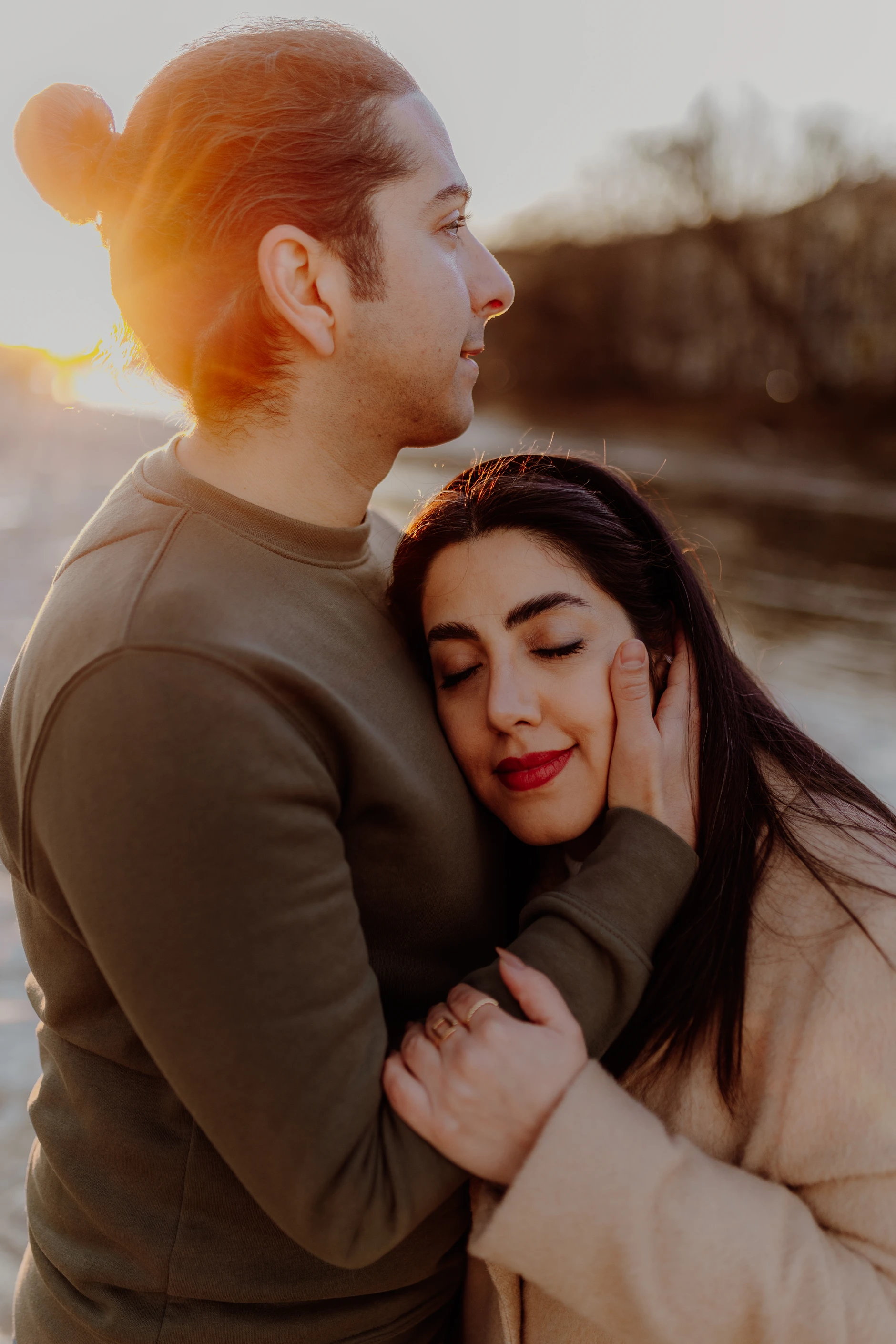 Wide shot: couple silhouetted against the shimmering water surface