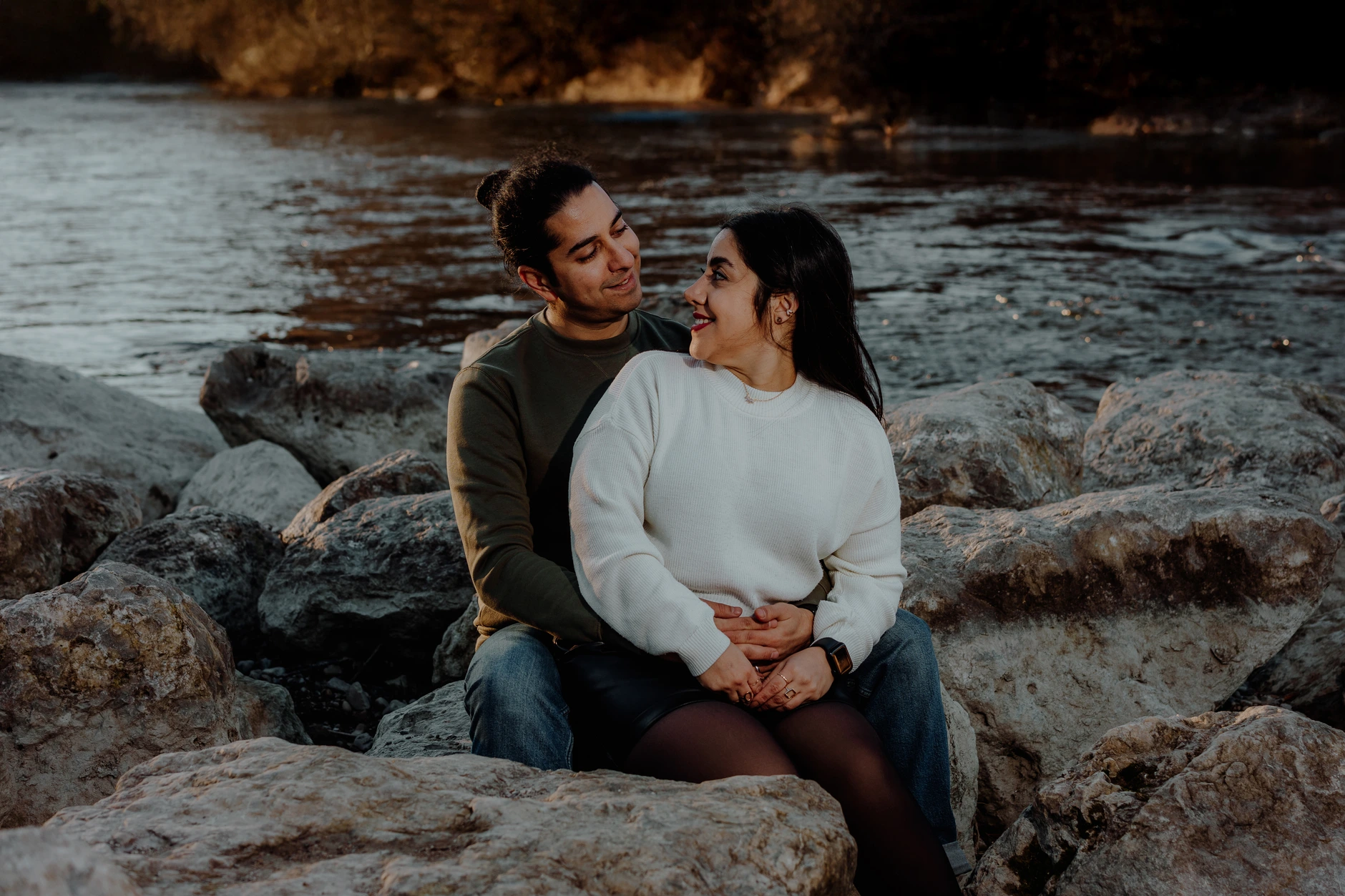 Seated couple smiling at each other by the river