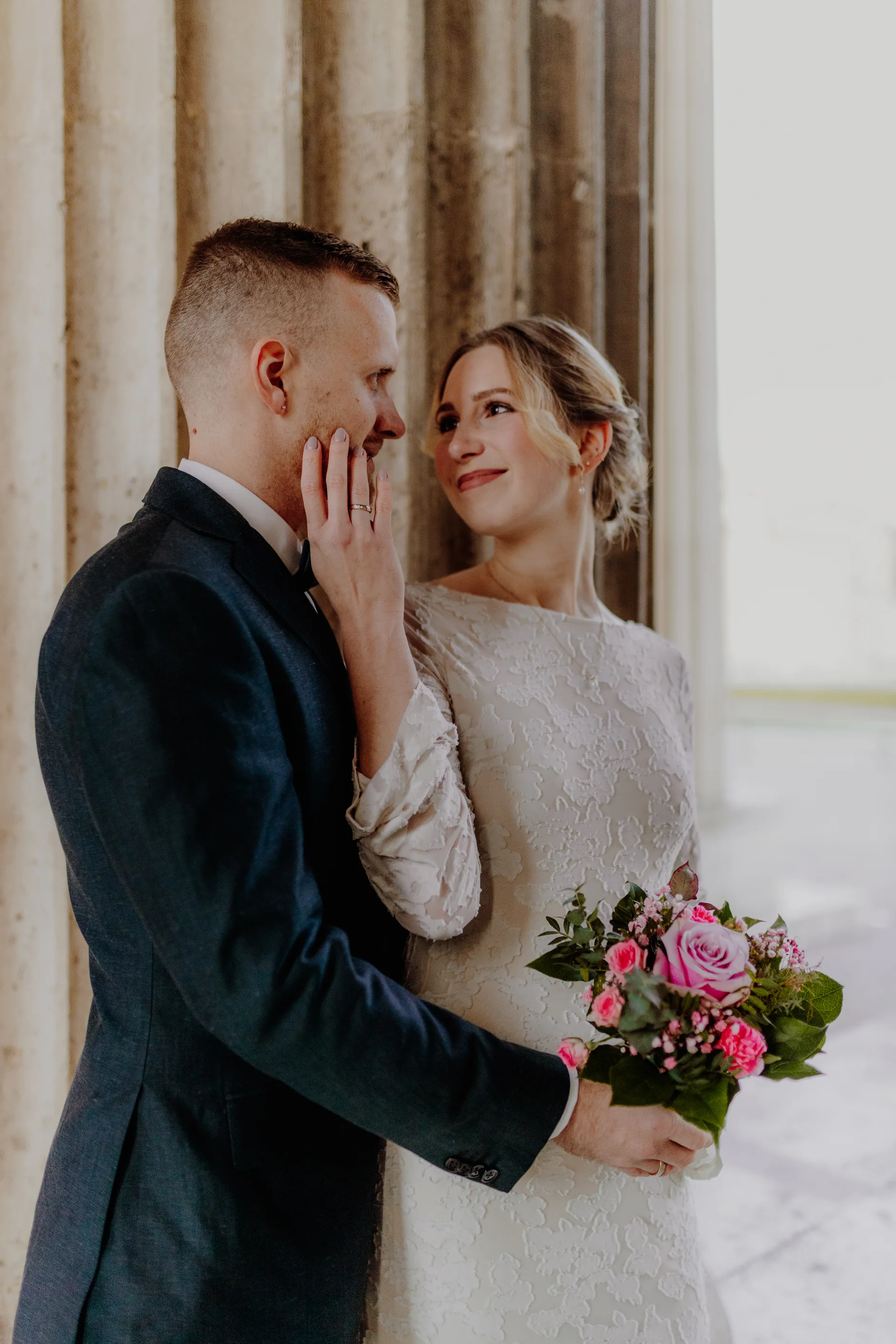 Bride and groom with bouquet in the colonnade