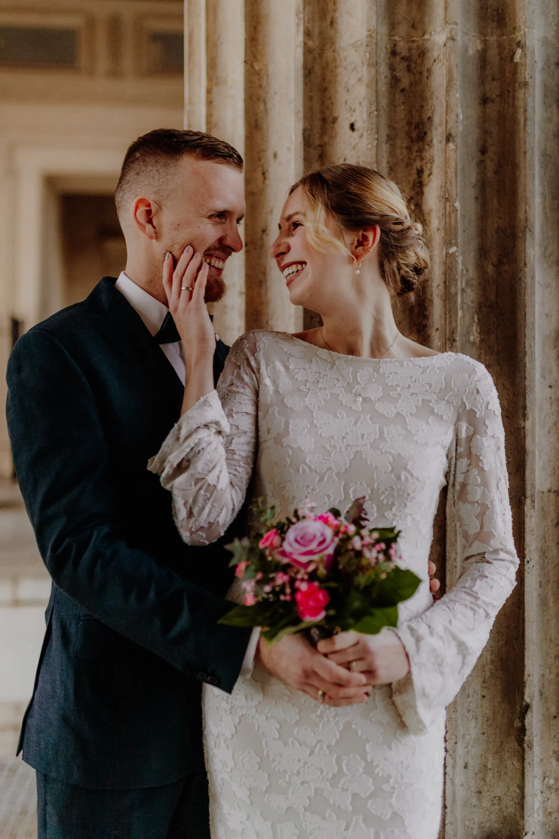 Couple portrait with bouquet against a bright column backdrop