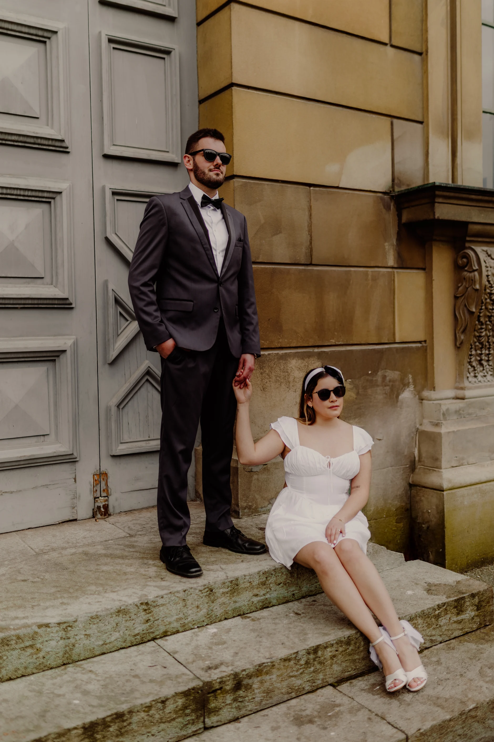 Groom portrait leaning by stone columns in the courtyard
