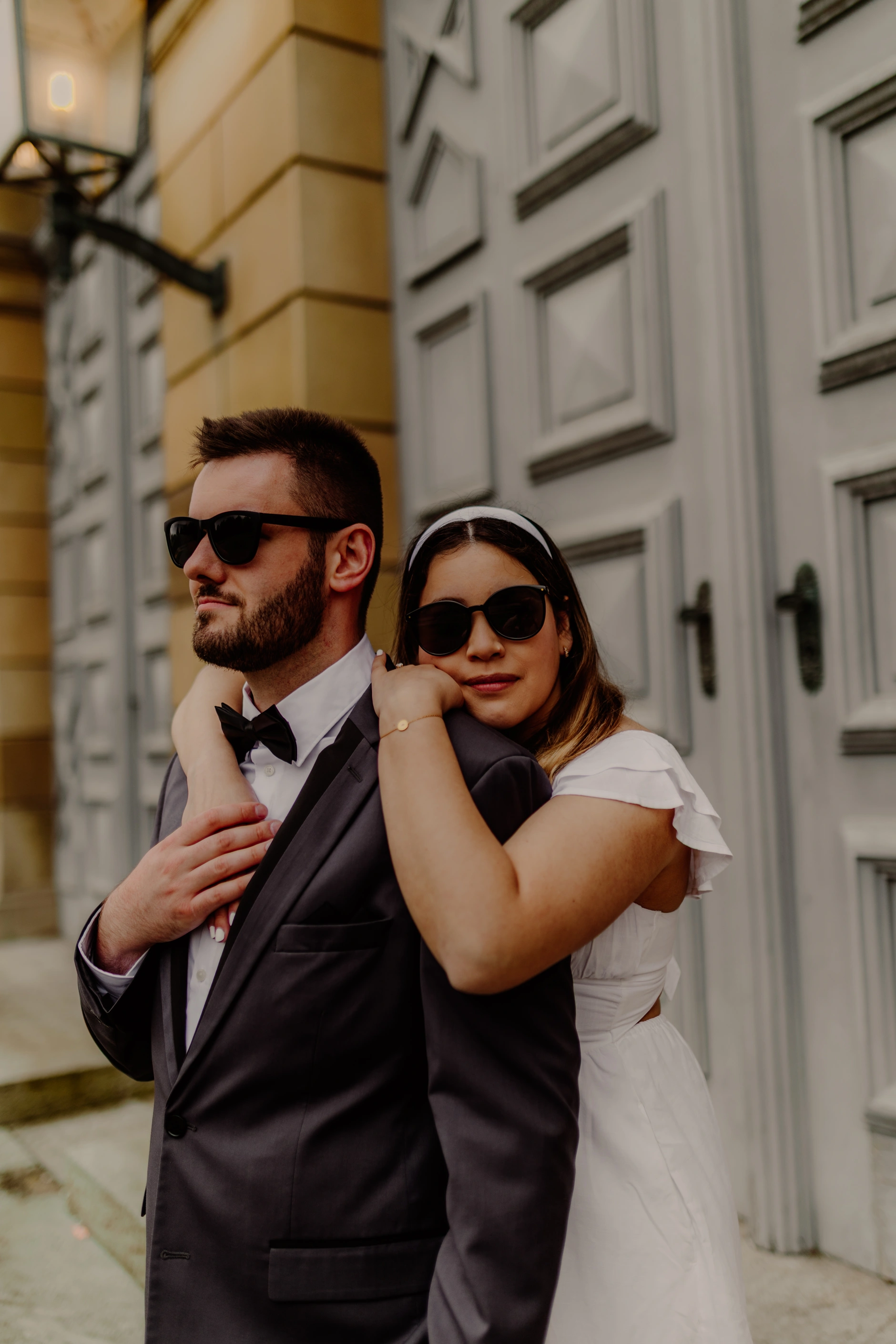 Couple in sunglasses in front of historic city hall facade