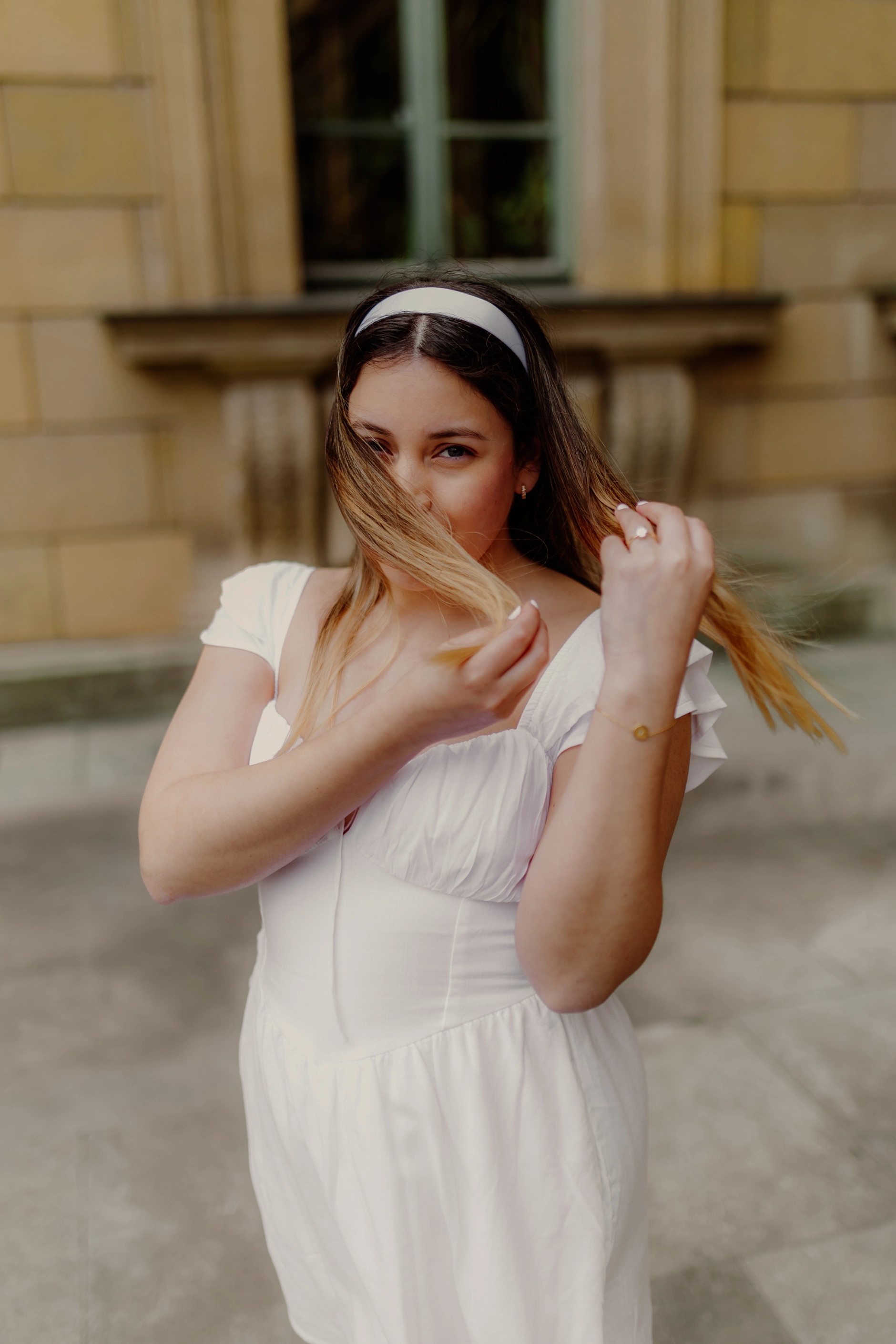 Bride portrait adjusting her veil in front of a historic building