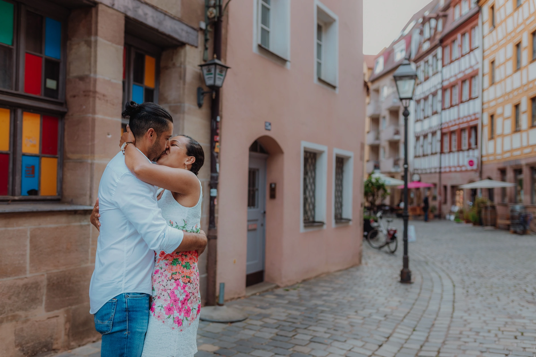 Couple embracing beside a pink Old Town facade
