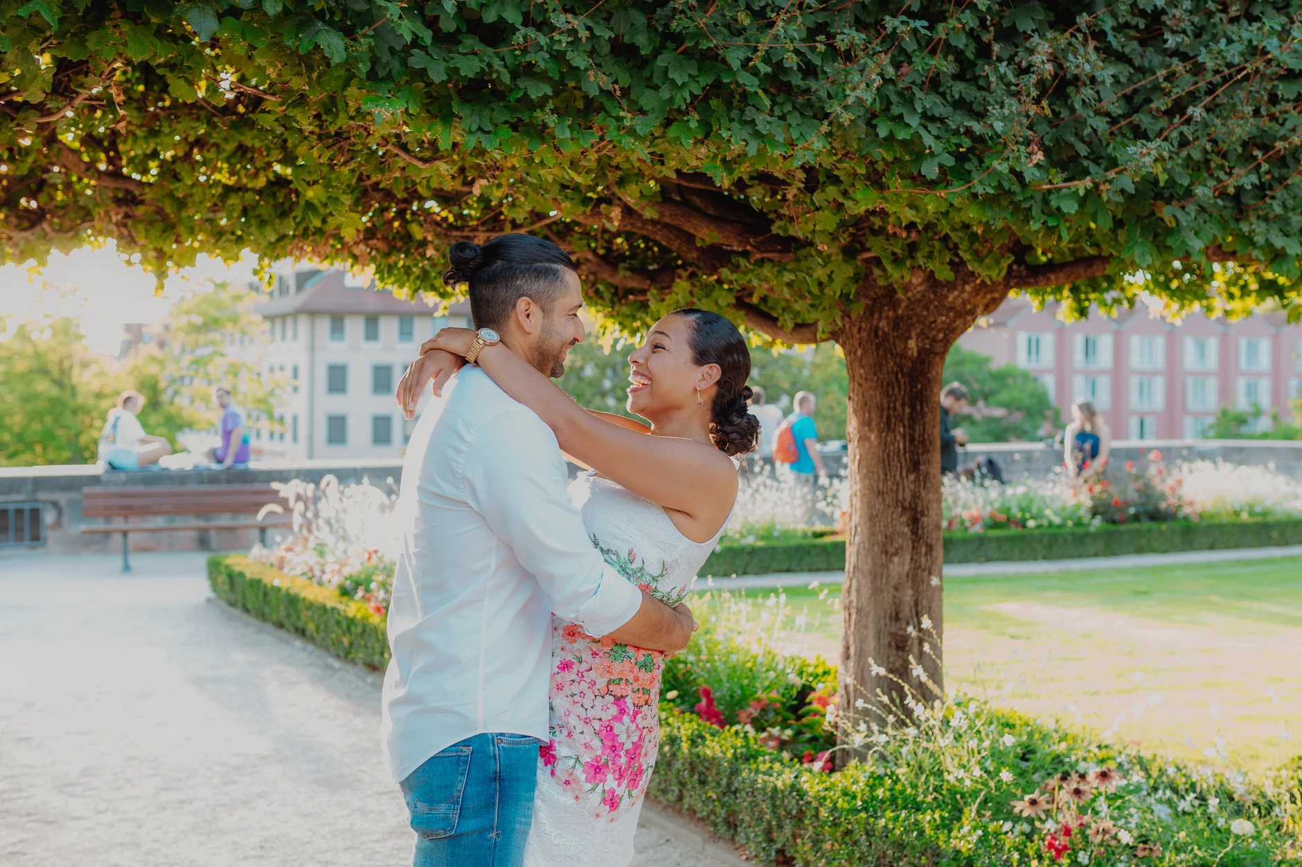Couple embracing under a large tree in the city park
