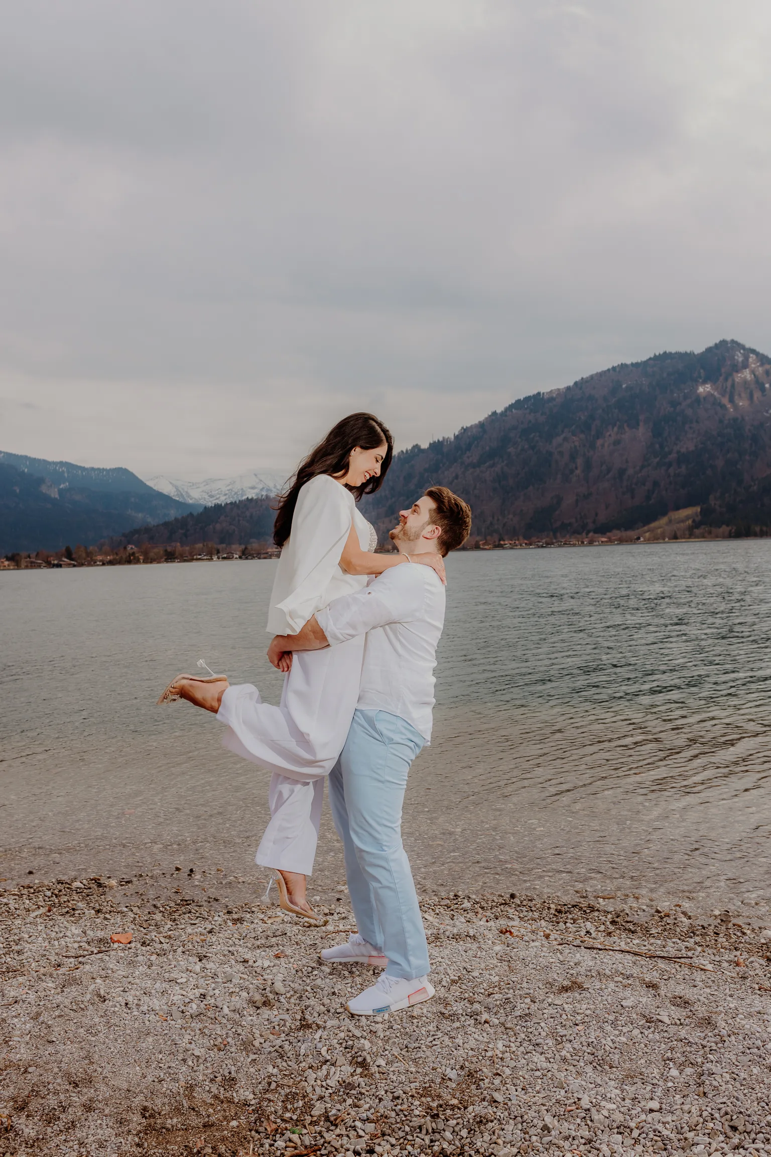 Bride walking along the pebble beach at the lake