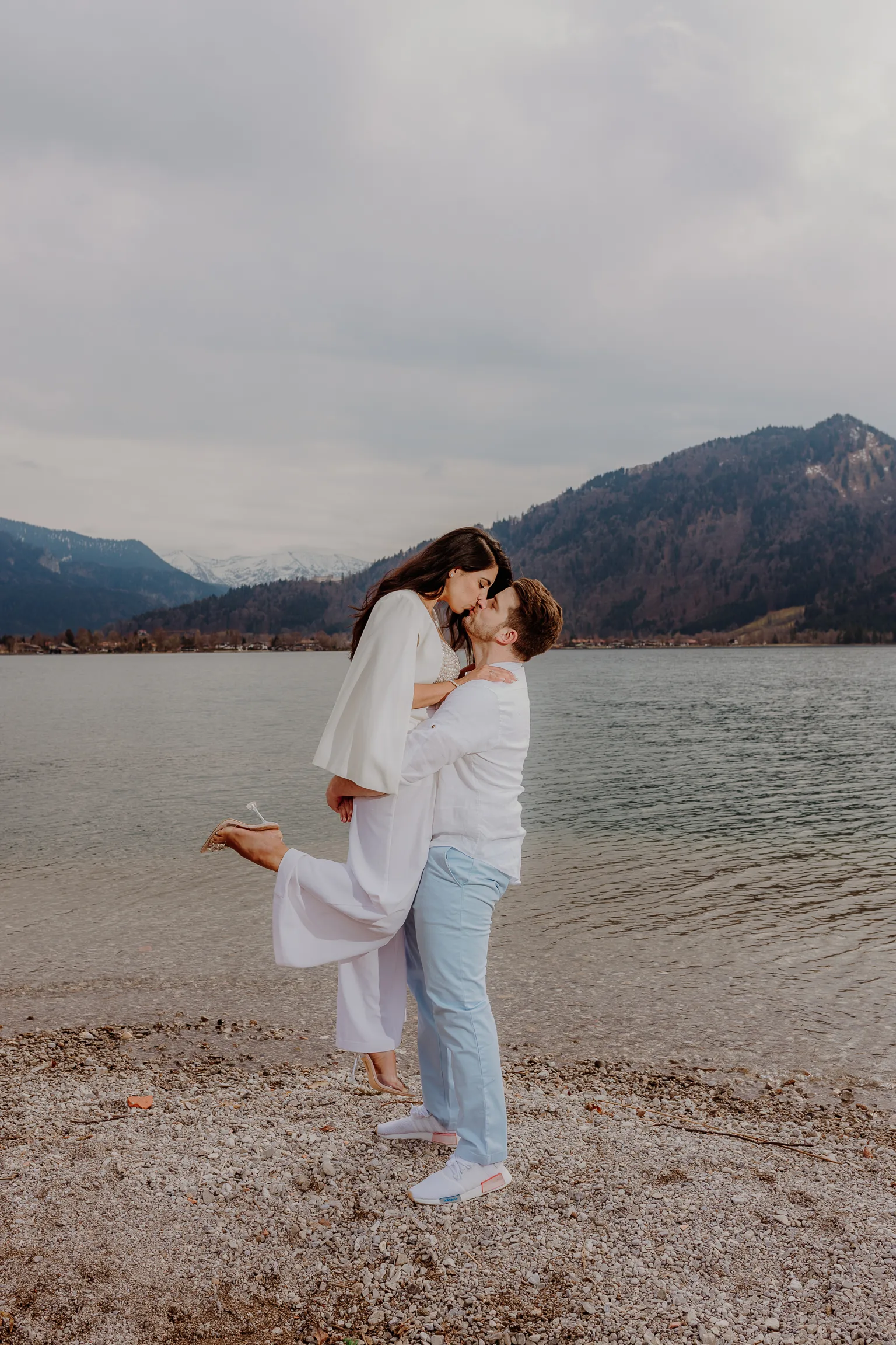 Couple embracing on the Tegernsee beach with mountains