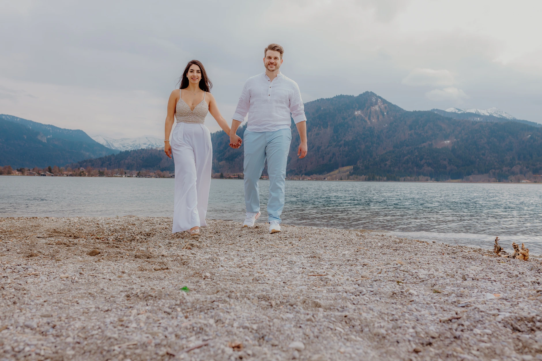Couple standing on the beach with mountain panorama