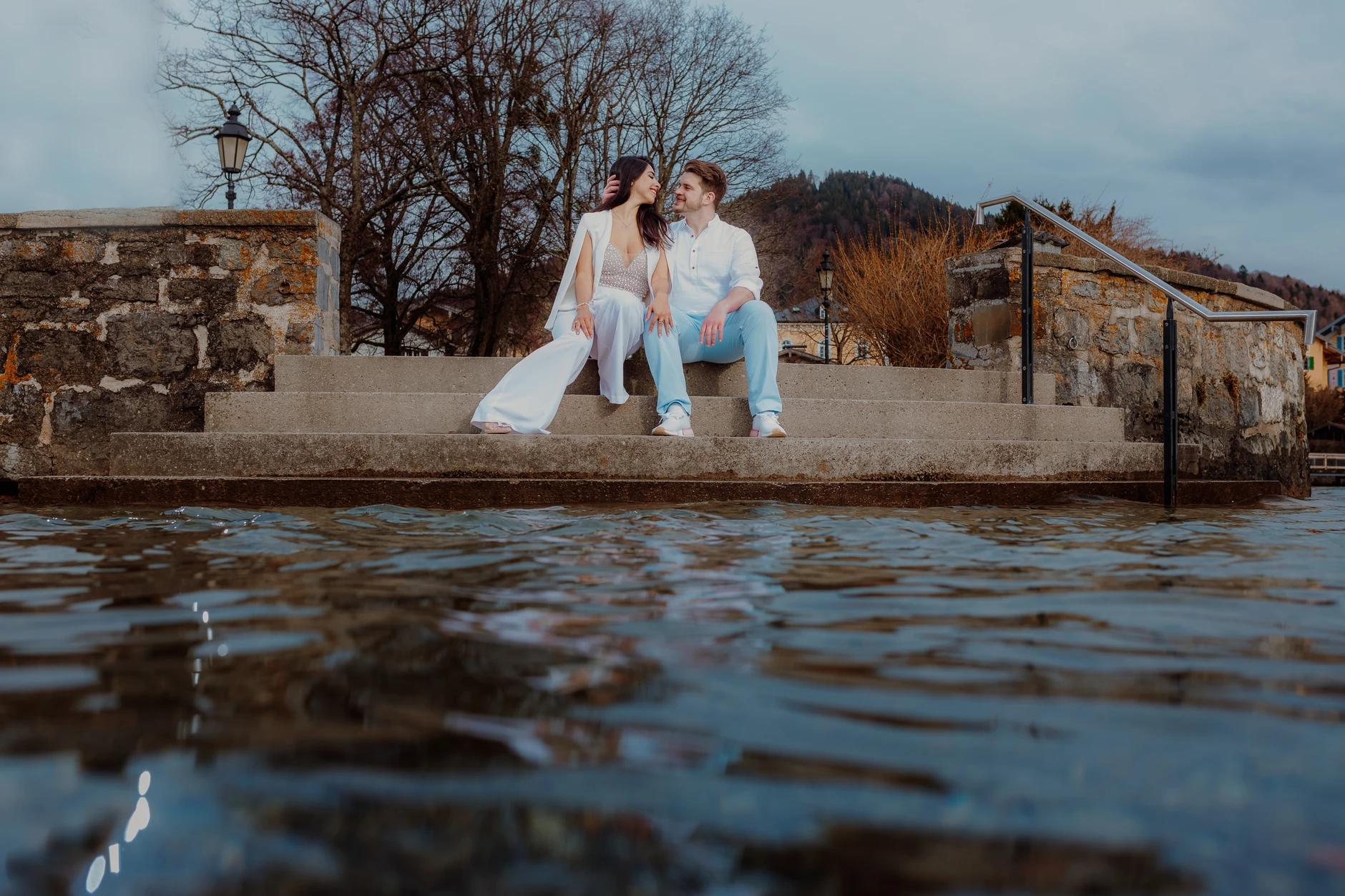 Couple hugging on the lakeshore with blue water