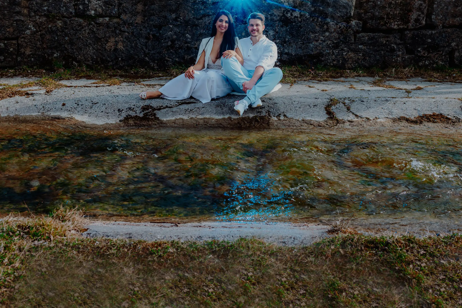 Couple stepping across shoreline rocks