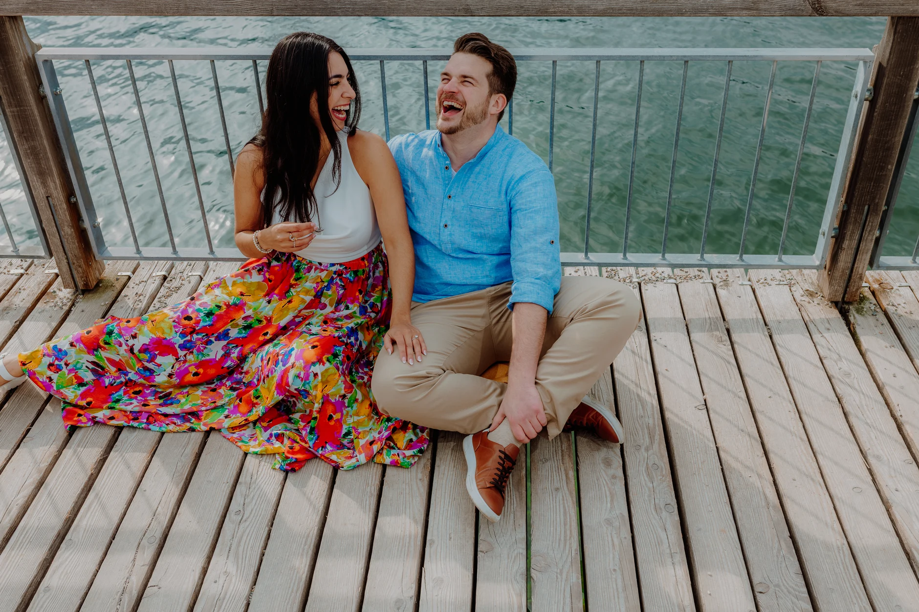 Couple sitting together on a blanket by the lakeside pier