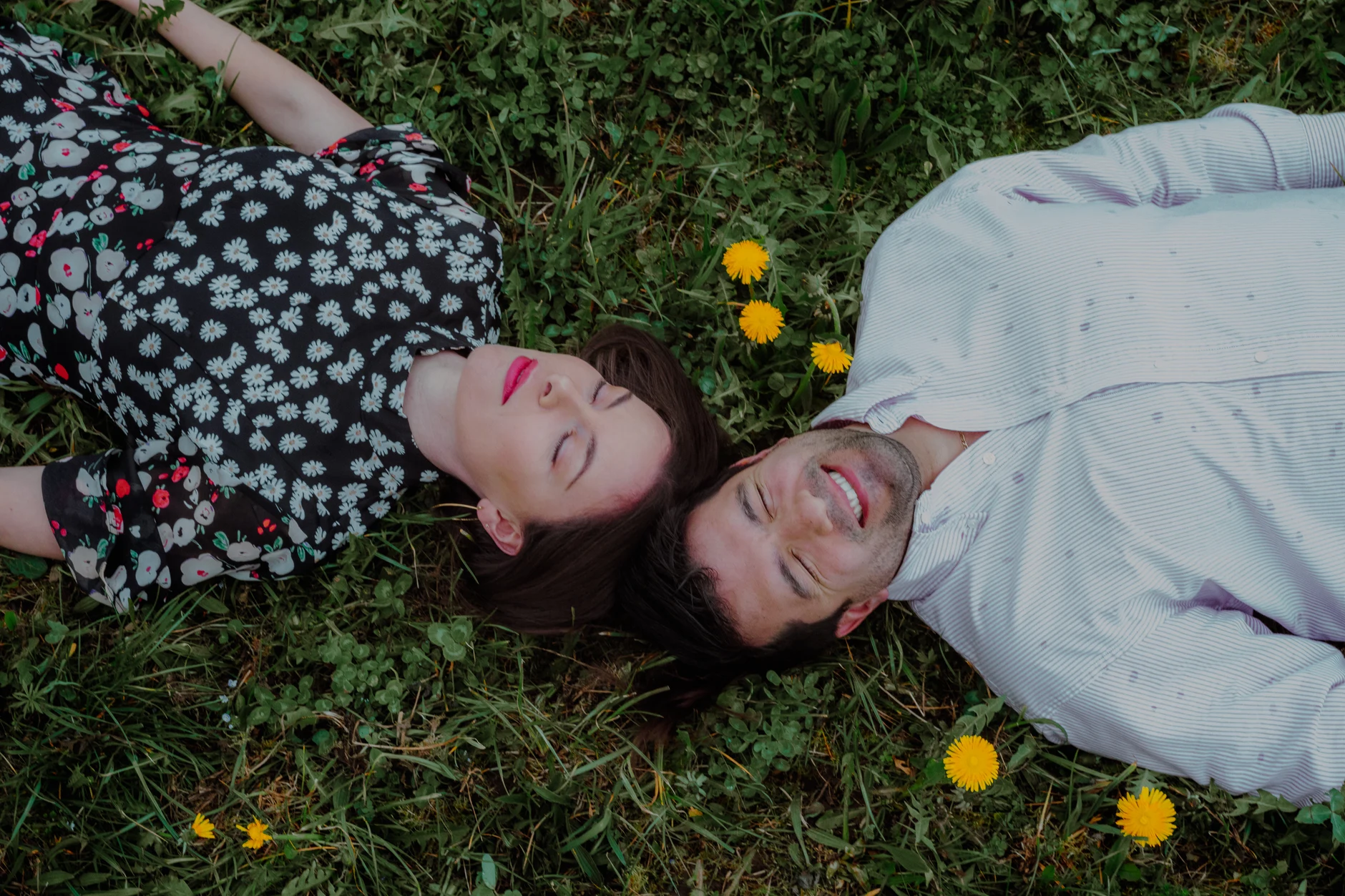 Couple laughing while lying on a flower meadow in Wolfratshausen, Upper Bavaria – couple photoshoot