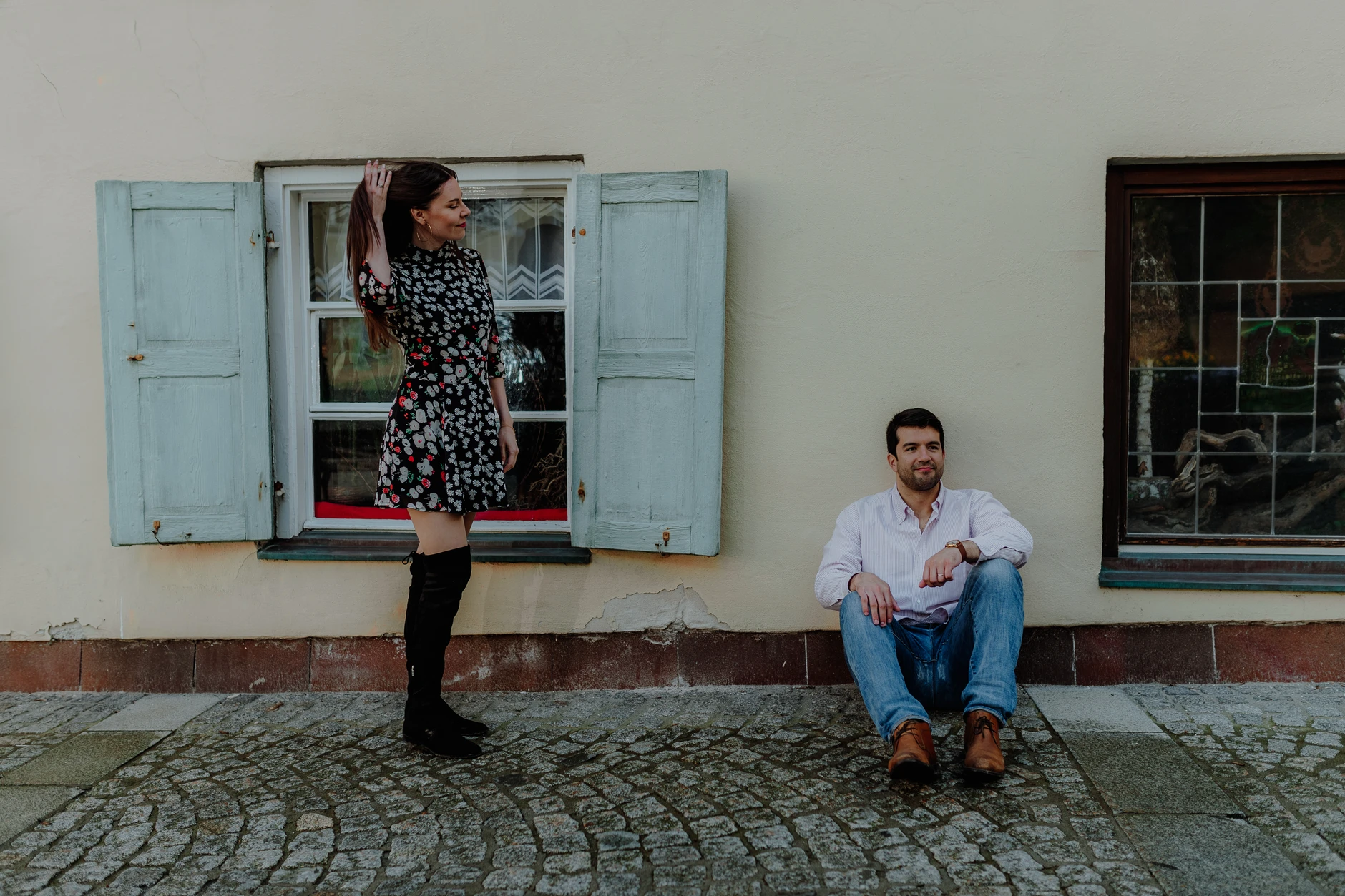 Man sitting by a turquoise facade and windows