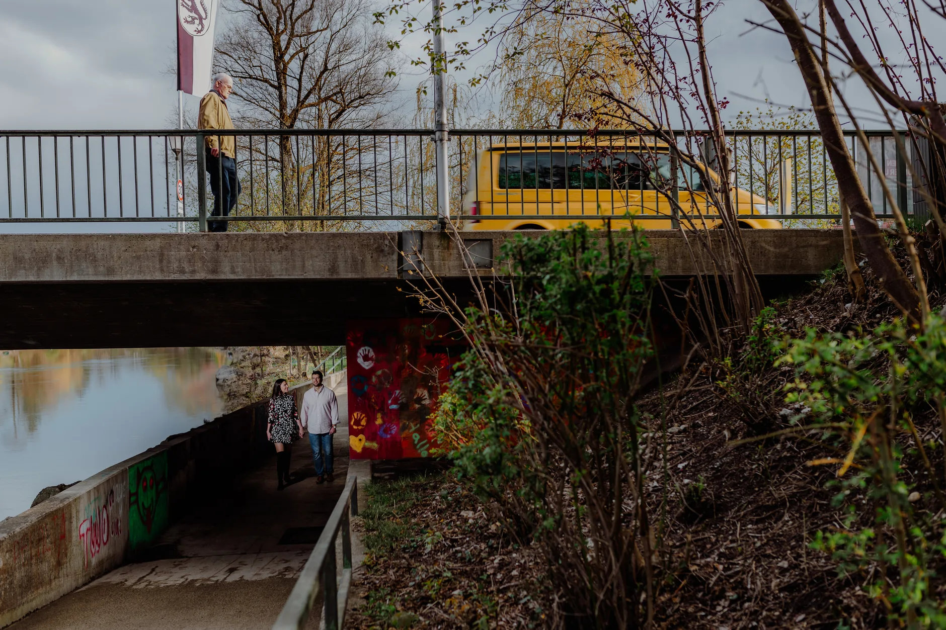 Couple on the bridge with a yellow commuter train behind them