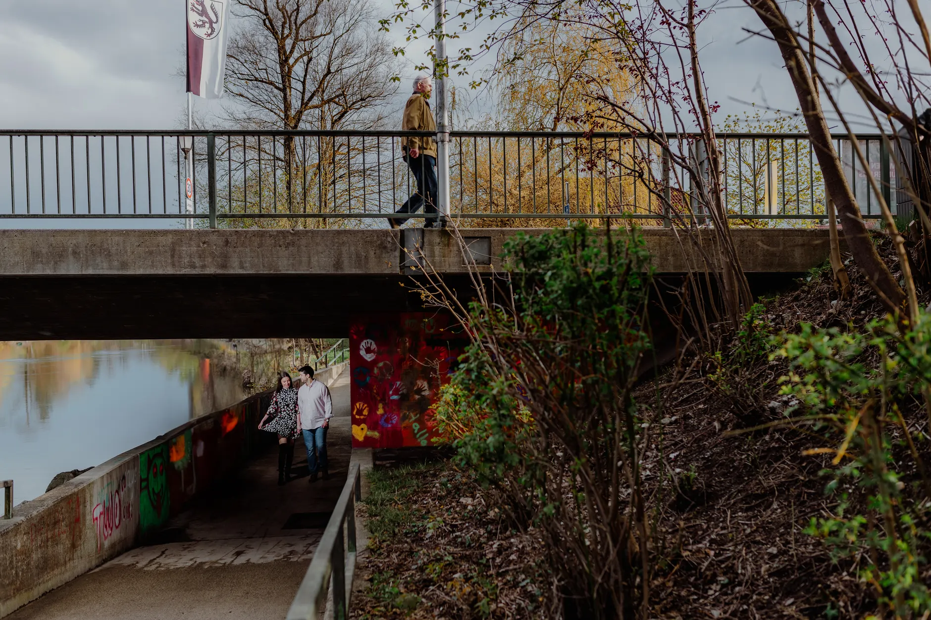 Underpass scene with graffiti, trees, and bridge above