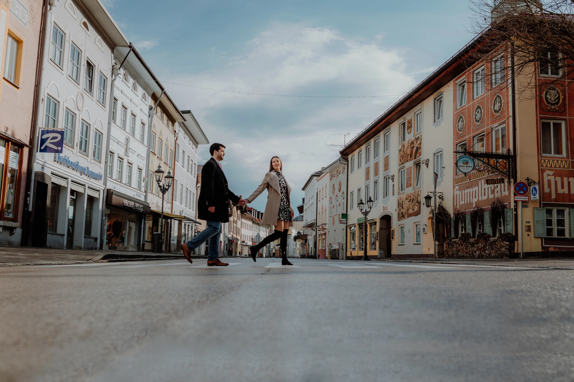 Wide shot of the couple crossing the old town street
